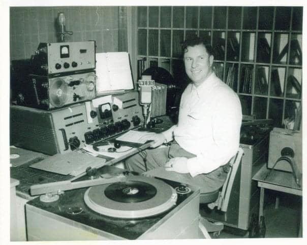 Man seated beside a turntable and radio equipment