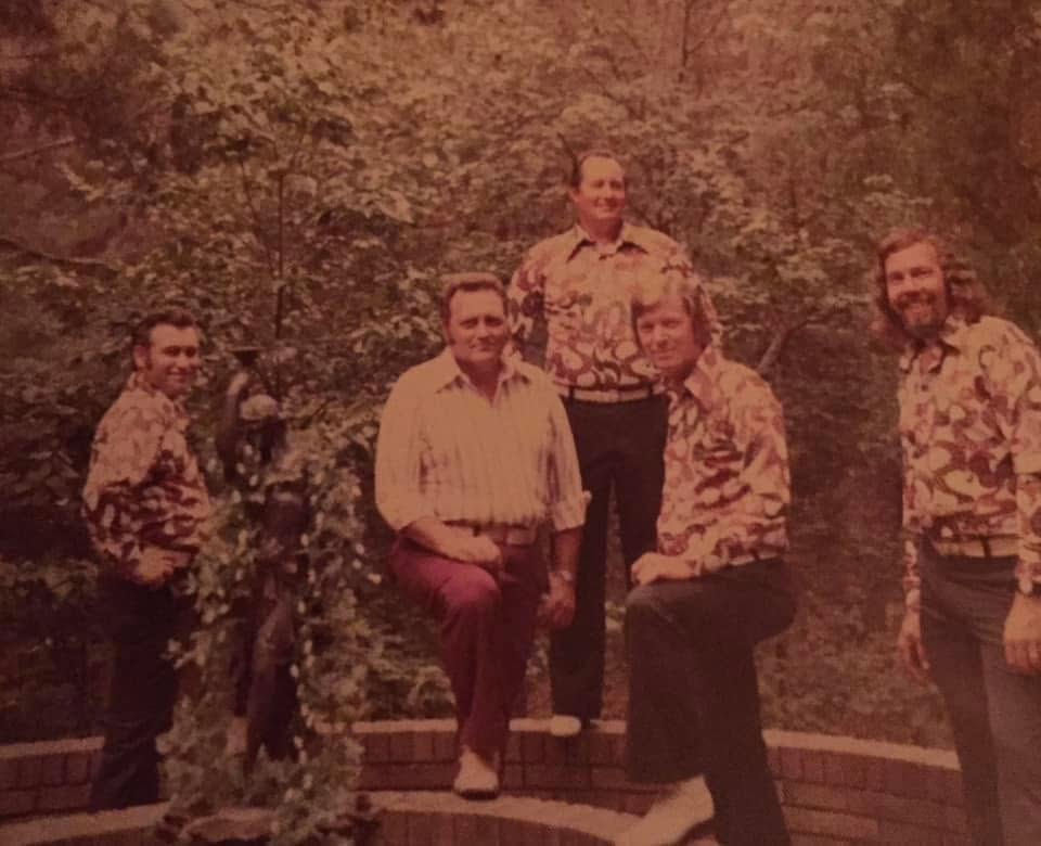 Five musicians posing together outdoors