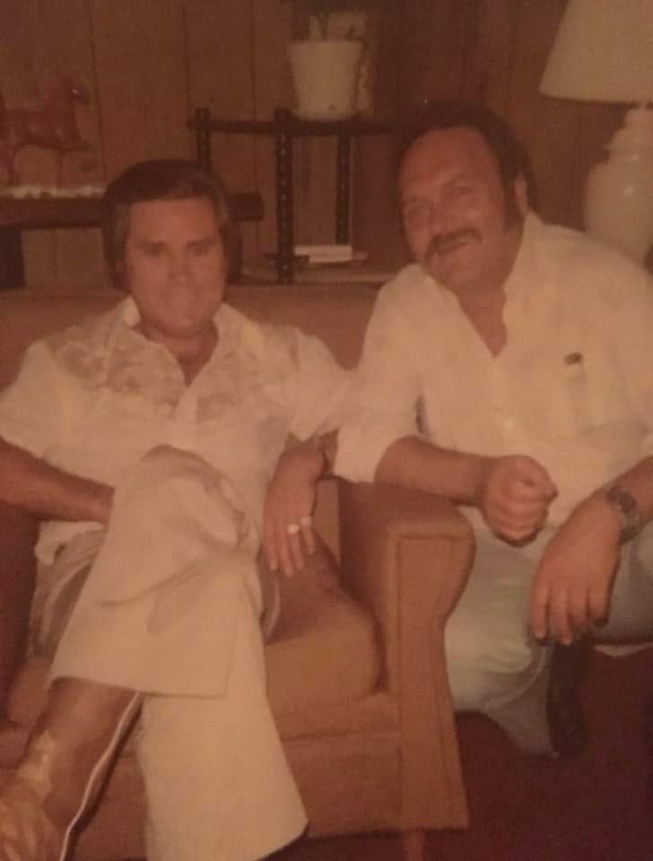 George Jones seated in a chair beside Carmol Taylor